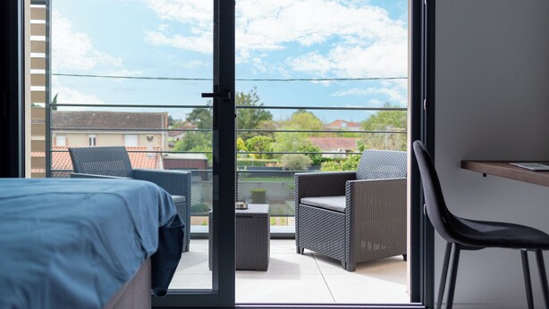 A balcony with wicker furniture, a bed, and a desk. - Studio Indigo - Centre - Albi (Albi)