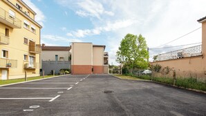 A parking lot with marked spaces, a building with balconies, and a tree. - Studio Indigo - Centre - Albi (Albi)