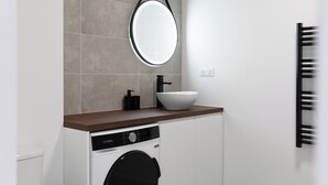 A modern bathroom with a round mirror, a white sink, and a black towel rack. - Studio Indigo - Centre - Albi (Albi)