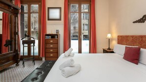 Hotellihuone, jossa on sänky, työpöytä, tuoli, lamppu ja ikkunasta avautuva näkymä ulos.