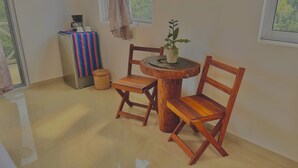A small, cozy room with a round wooden table and two wooden chairs. A coffee maker and cups are on the table, and a potted plant is on the table's center. A wicker basket is on the floor next to the table. - Hotel Ich Ha Tulum - Adults Only  (Tulum)