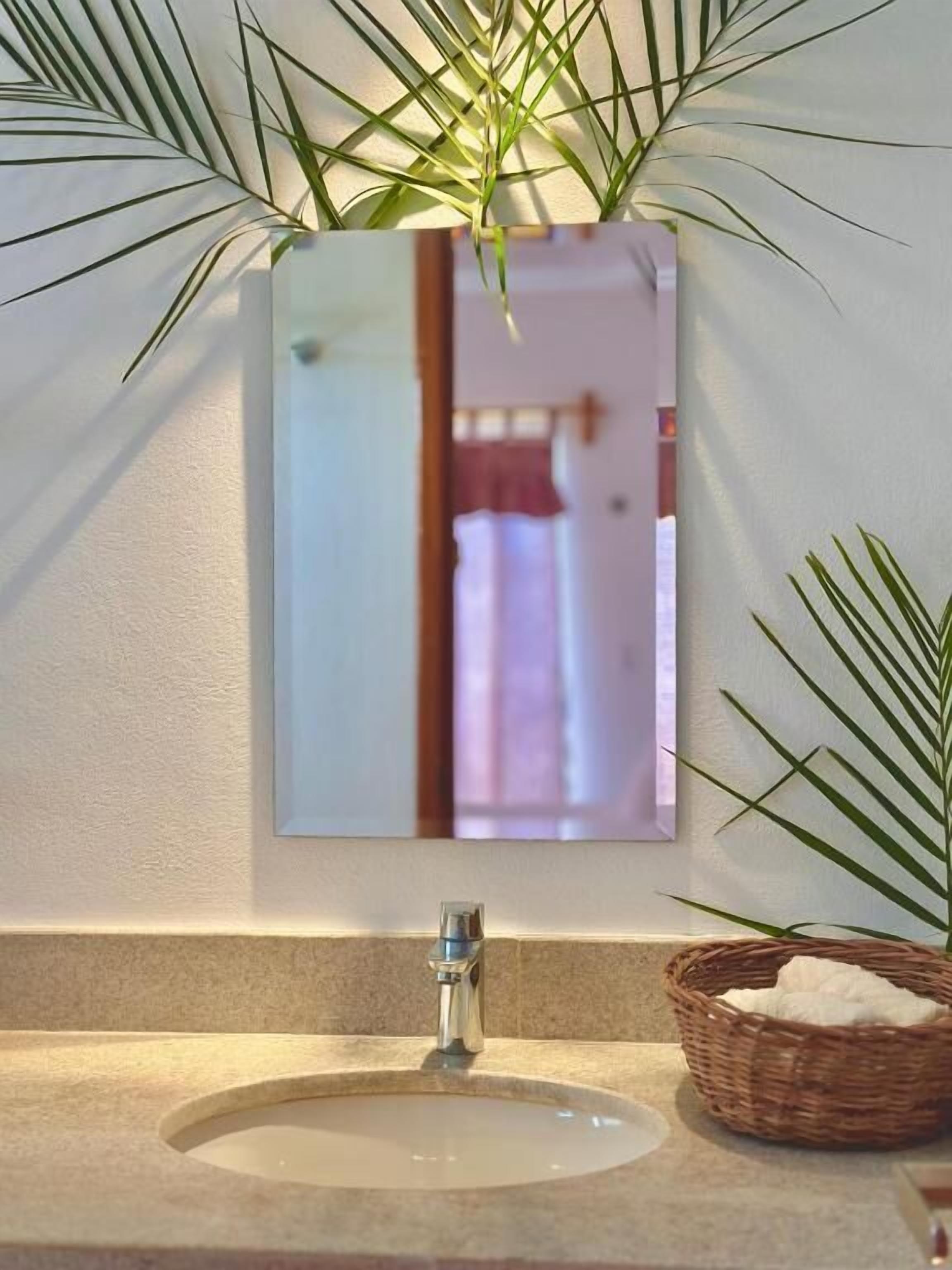 Ein Badezimmer mit Waschbecken, Spiegel und einer Topfpflanze.