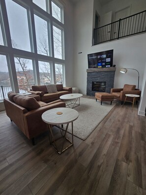 A spacious living room with a fireplace, large windows, and a balcony. - Waterfront Retreat One (Rocky Mount)