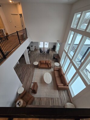 A spacious living area with a high ceiling, large windows, and a wooden floor. - Waterfront Retreat One (Rocky Mount)