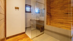 Ein modernes Badezimmer mit einer Duschkabine aus Glas, Holzvertäfelung, einem integrierten Waschbecken und einem kleinen Fenster.