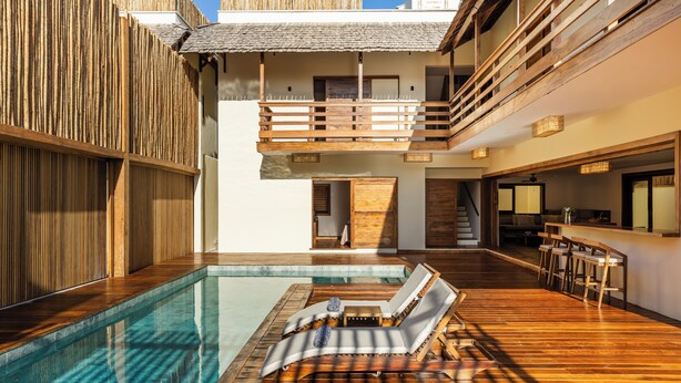 Ein Poolbereich mit Holzboden, Liegestühlen und einer kleinen Bar.