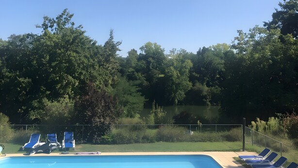 A swimming pool with lounge chairs and a fenced area.