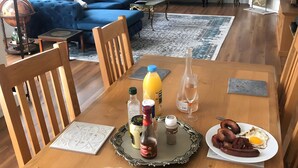 A dining area with a wooden table set for breakfast, including plates of food, condiments, and a kettle. - Gite La Garonne with Shared Pool, Communal Garden, and Wi-Fi (Le Lédat)