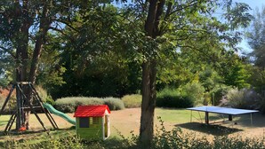 A playground with a slide and swings, a small house-like structure, and a ping pong table. - Gite La Garonne with Shared Pool, Communal Garden, and Wi-Fi (Le Lédat)