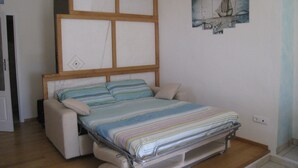 A compact bed with a wooden headboard and a striped mattress. - Nature Refuge with Sea Views and Dream Sunsets on Elba Island (Toscana)