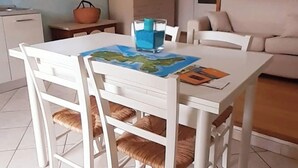 A dining area with a white table, chairs, and a map on the table. - Nature Refuge with Sea Views and Dream Sunsets on Elba Island (Toscana)