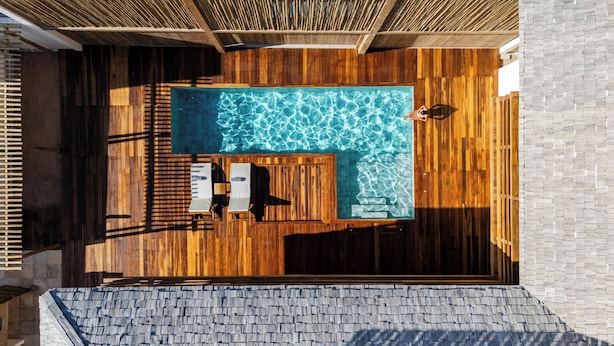 A rooftop pool with wooden decking and a stone wall.