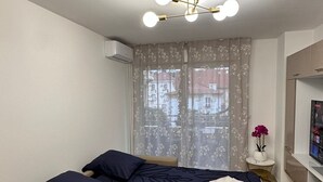 Un dormitorio con cama, sofá cama, televisor y ventana con cortinas.