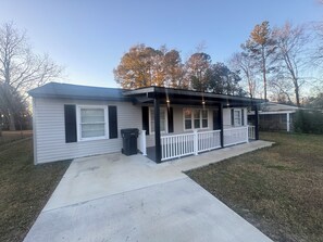 A single-story house with a covered porch and a small attached garage. - 4-bedroom house. 1 King & 3 Queens in delightful Augusta. Your “Place of Peace” (Augusta)