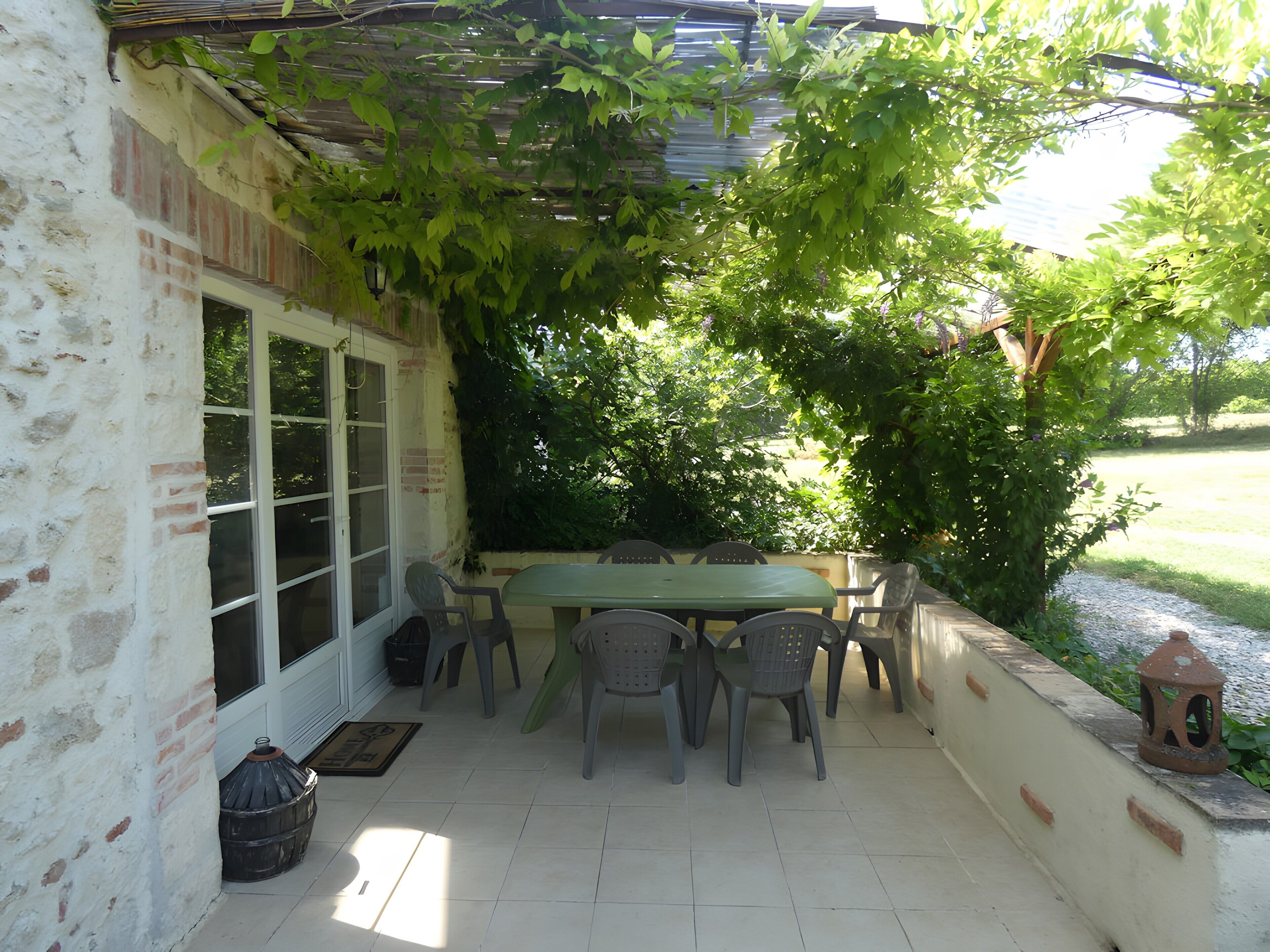 A patio with a table and chairs, a door, and a brick wall.