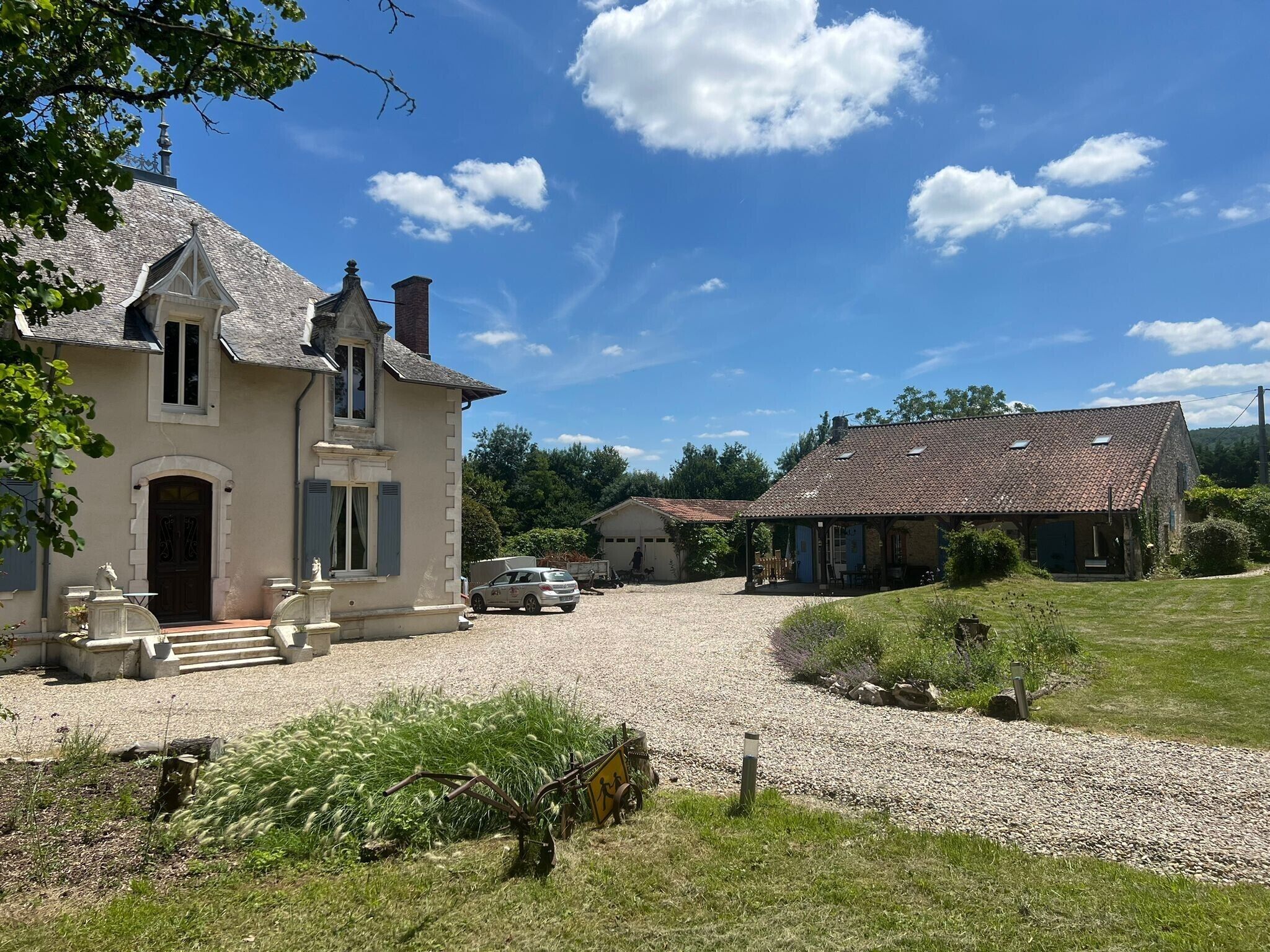 Une grande maison avec une allée en gravier et un porche abrité.