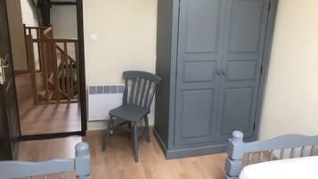 Un dormitorio con una cama de madera, un armario gris y una silla.