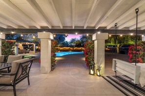 Un espace extérieur aménagé avec une terrasse, une piscine, des sièges et des guirlandes lumineuses.