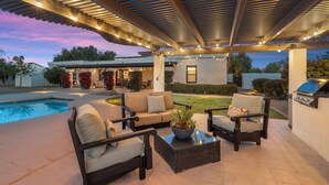 Une terrasse extérieure avec une piscine, un espace salon et un barbecue.