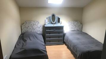 A bedroom with two single beds, a dresser with drawers, a mirror, and a skylight.