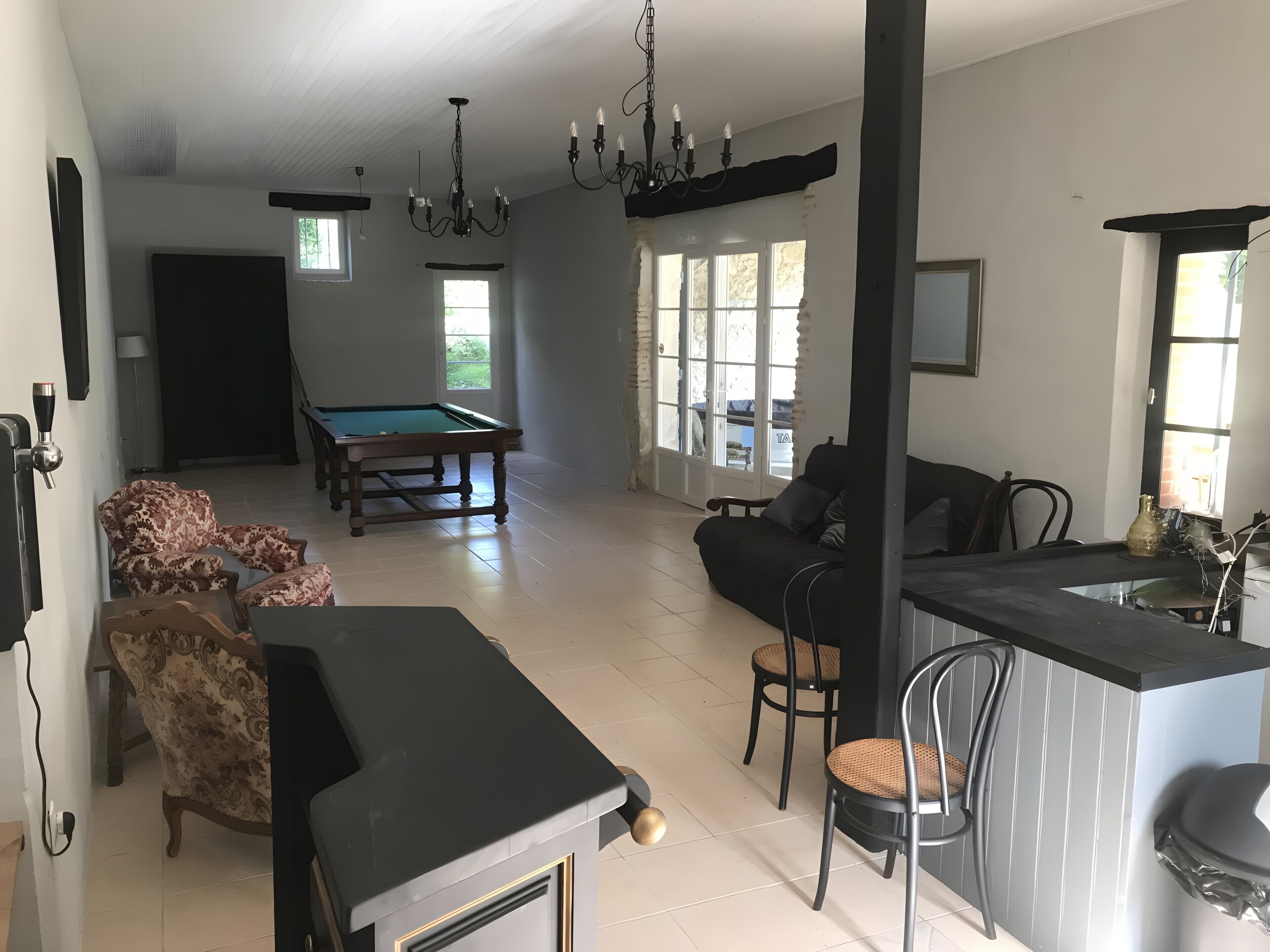 A spacious living area with a pool table, a sofa, and a dining area with chairs.