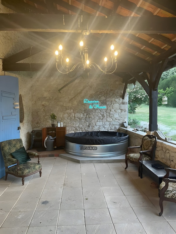 Une pièce chaleureuse avec un mur en pierre, un jacuzzi, une porte bleue et une vue sur le jardin.