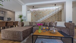 Ein modernes Wohnzimmer mit einer Eckcouch, einem Couchtisch und einer Treppe mit einer Steinwand.