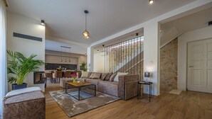 Ein modernes Wohnzimmer mit Sofa, Hocker, Couchtisch und einer Treppe zu einer oberen Ebene.