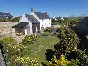 Ein Wohnhaus mit Steinmauer, Holzterrasse und Garten mit gelben Blumen.
