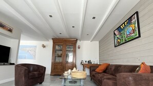 Een woonkamer met een bruine bank, een glazen salontafel, een houten kast en een kaart aan de muur.