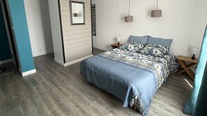 Een slaapkamer met een bed, nachtkastjes, een spiegel en een wandlamp.