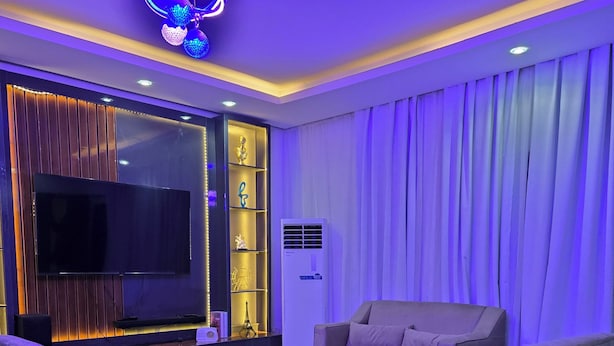 A modern living room with a flat-screen TV, comfortable seating, and decorative lighting. - Spacious 3-bedroom apartment with AC in gorgeous Lagos (Lagos)
