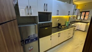 A modern kitchen with white cabinets, a stainless steel refrigerator, and a built-in oven. - Spacious 3-bedroom apartment with AC in gorgeous Lagos (Lagos)