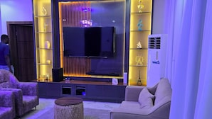 A modern living room with a flat-screen TV, comfortable seating, and ambient lighting. - Spacious 3-bedroom apartment with AC in gorgeous Lagos (Lagos)
