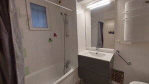 Een moderne badkamer met een bad, een wastafel met spiegel en een toilet.