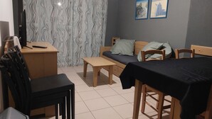 Een kleine kamer met een bed, een bureau, een stoel en een bijzettafeltje.