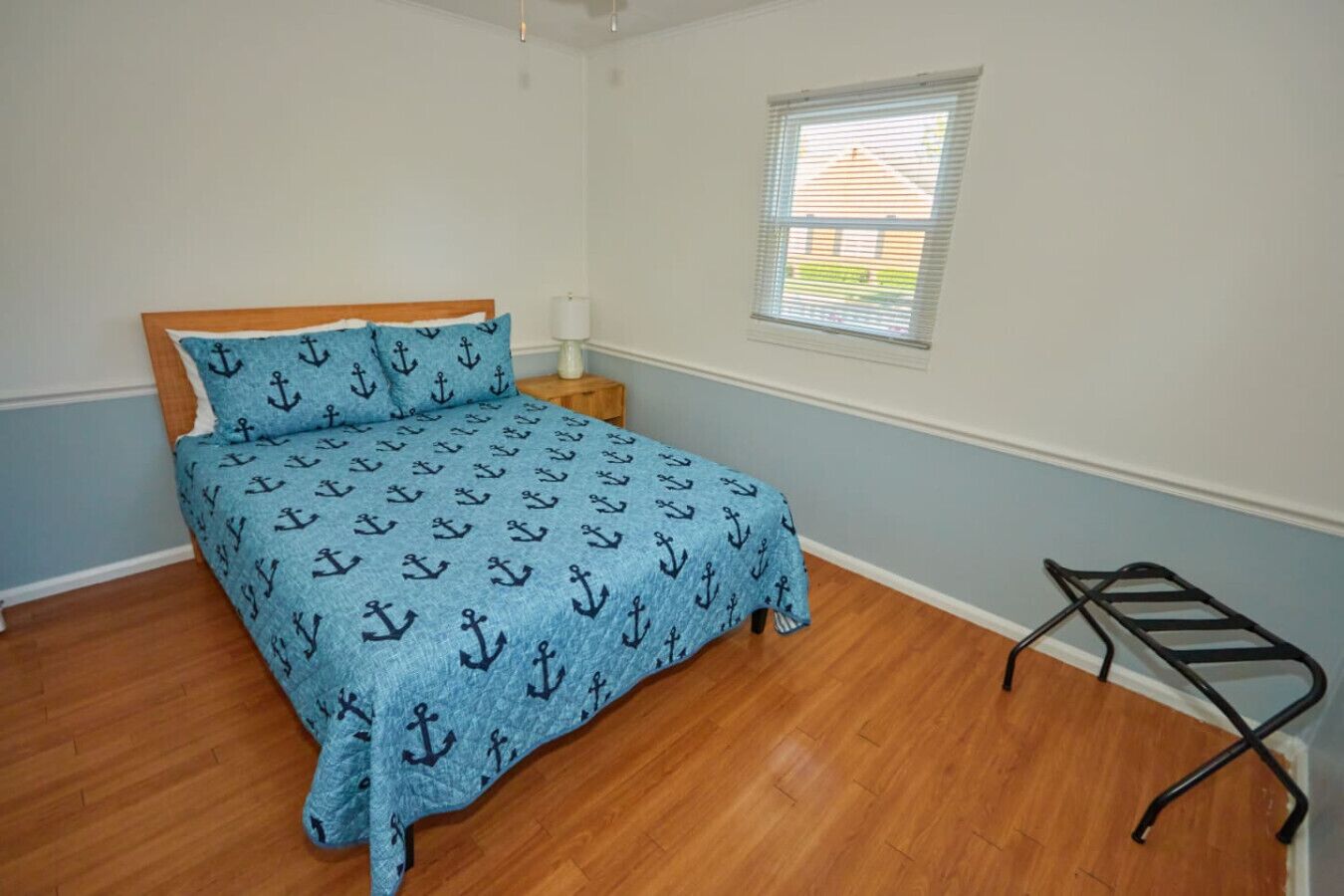 A bedroom with a bed, a nightstand, a window, and a black metal rack.