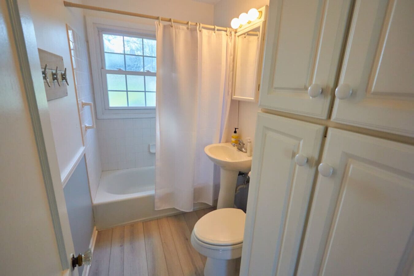 A bathroom with a bathtub, toilet, sink, and a window.