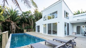 A modern house with a swimming pool, deck, and lounge chairs.