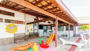 A covered outdoor area with a children's play area, including slides and play structures, and a wall with a logo and artwork. - A retreat with a garden and swimming pool next to the lagoon. (Iguaba Grande)