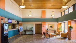 A spacious lobby with a reception desk, seating area, and a large window. - St. John's Inn (Myrtle Beach)