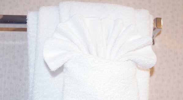 A white towel folded in a fan shape on a metal towel rack. - St. John's Inn (Myrtle Beach)