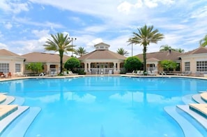 A large swimming pool with lounge chairs and palm trees, surrounded by buildings with a central pavilion. - Private Pool-hot Tub, Near Disney, 4 BR, King Beds (Kissimmee)