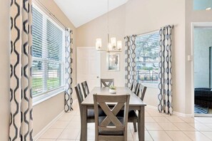 A dining area with a table, chairs, and a chandelier. - Private Pool-hot Tub, Near Disney, 4 BR, King Beds (Kissimmee)