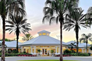 A hotel with a central atrium, palm trees, and a sunset sky. - Private Pool-hot Tub, Near Disney, 4 BR, King Beds (Kissimmee)