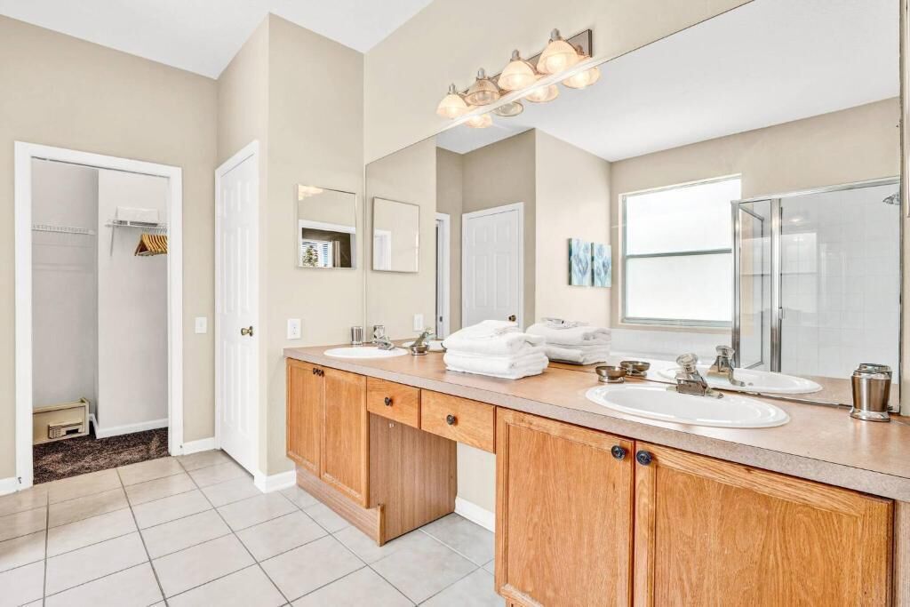 A bathroom with two sinks, wooden cabinets, and a large mirror.