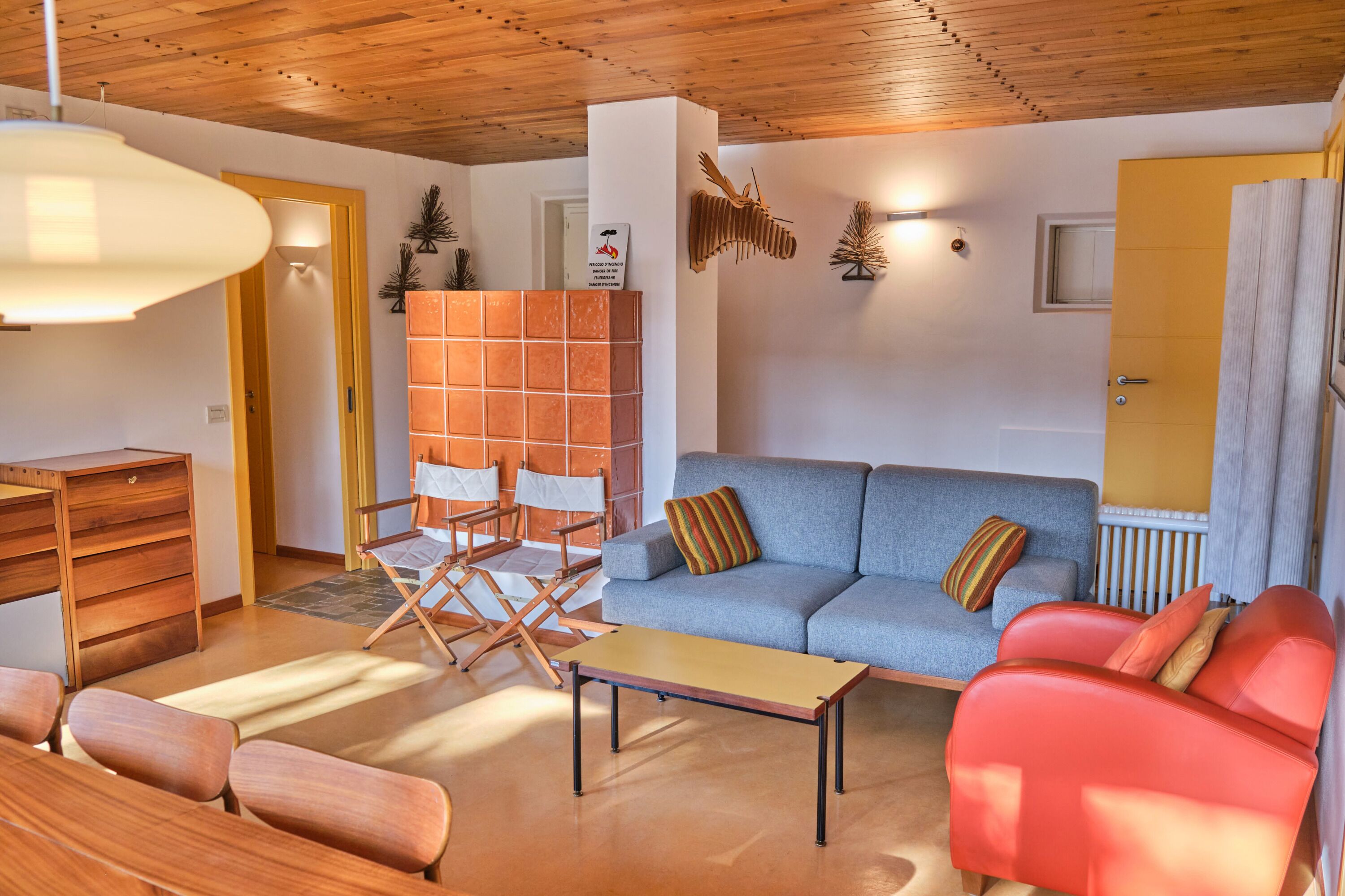 Ein modernes Wohnzimmer mit einem blauen Sofa, einem roten Sessel, einem Holztisch und einem Regiestuhl.