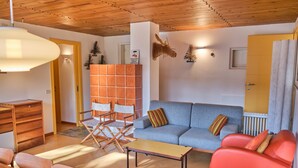 Una sala de estar moderna con un sofá azul, un sillón rojo, una mesa de centro de madera y una silla de director.