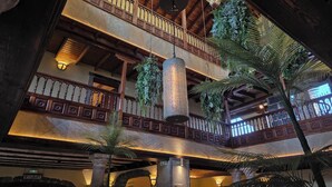 Un atrium de diversos nivells amb balcons de fusta, plantes penjants i columnes de pedra.