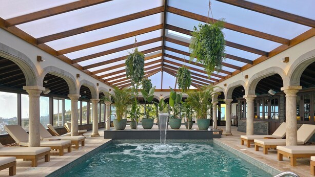 Zona de piscina amb gandules, una font central i plantes en testos.